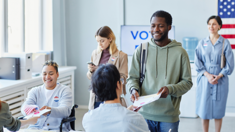 two Black people getting their voting ballots at a polling place.